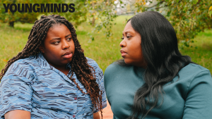 Two young people sitting on a park bench talking. The Young Minds logo is in the top left of the image.