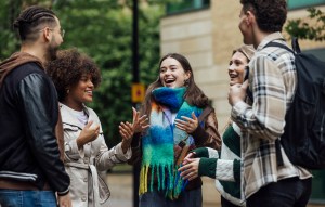A small group of university students standing together talking in the city on an autumn day in Newcastle, England.
